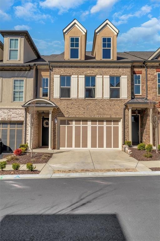 townhome / multi-family property featuring an attached garage, concrete driveway, and brick siding