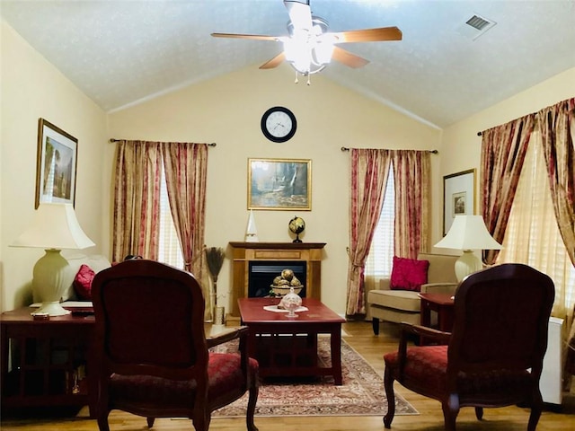 sitting room featuring a ceiling fan, wood finished floors, visible vents, lofted ceiling, and a fireplace