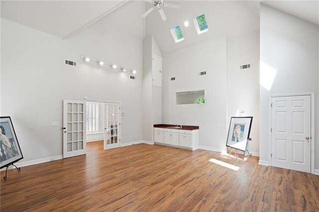4340 Candacraig, Johns Creek, GA 30022 - unfurnished living room with high vaulted ceiling, a skylight, wood finished floors, a ceiling fan, and french doors
