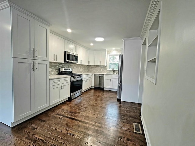 kitchen featuring dark wood-type flooring, stainless steel appliances, white cabinetry, ornamental molding, and sink