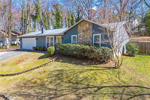 view of front of home featuring aphalt driveway, an attached garage, a front yard, fence, and stone siding