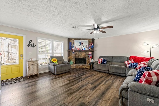 living room featuring crown molding, a textured ceiling, dark wood-style flooring, and a stone fireplace