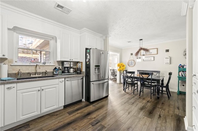 kitchen featuring visible vents, dark wood-style floors, stainless steel appliances, white cabinetry, and a sink