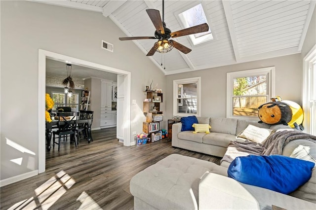 living area with a skylight, dark wood-style flooring, beam ceiling, visible vents, and baseboards