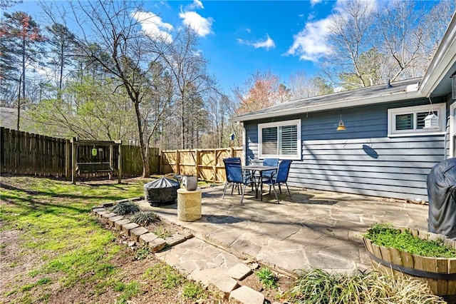 view of patio with a fire pit, outdoor dining area, and a fenced backyard