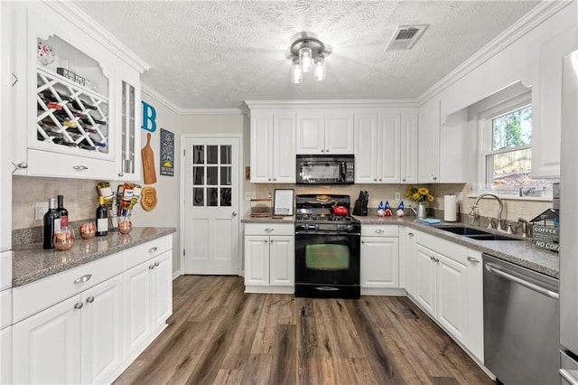 kitchen featuring dark wood-style flooring, a sink, visible vents, white cabinets, and black appliances