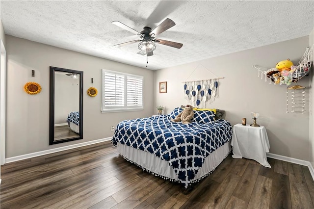 bedroom with dark wood finished floors, a textured ceiling, baseboards, and ceiling fan