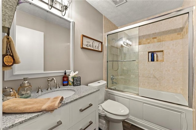 bathroom with visible vents, bath / shower combo with glass door, toilet, a textured ceiling, and vanity