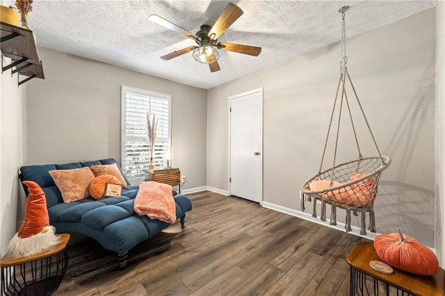 living area featuring a textured ceiling, wood finished floors, visible vents, baseboards, and a ceiling fan