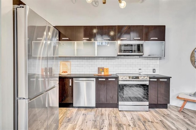 kitchen with stainless steel appliances, dark countertops, backsplash, dark brown cabinetry, and modern cabinets