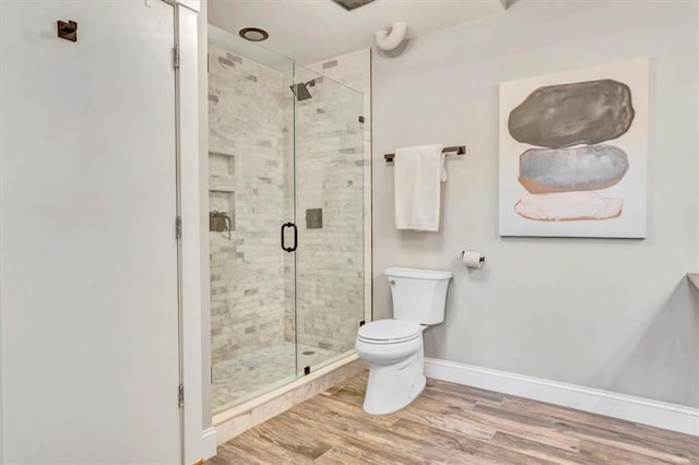 bathroom featuring a stall shower, wood finished floors, and toilet