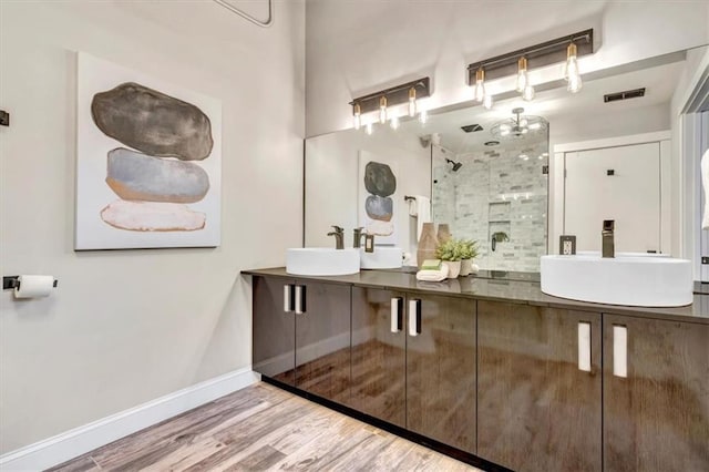 bathroom featuring visible vents, a stall shower, a sink, wood finished floors, and baseboards