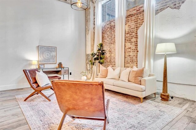 sitting room featuring wood finished floors, a towering ceiling, and baseboards