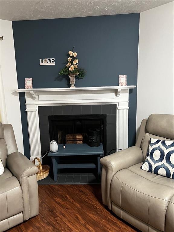 living room featuring a textured ceiling, wood finished floors, and a tile fireplace