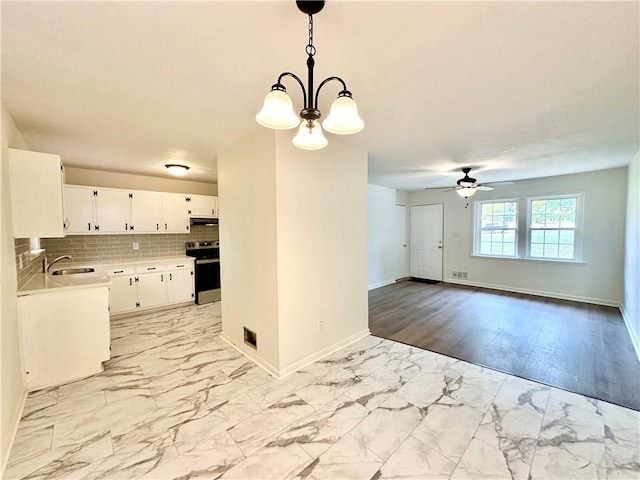 kitchen featuring hanging light fixtures, backsplash, stainless steel electric stove, white cabinets, and ceiling fan with notable chandelier