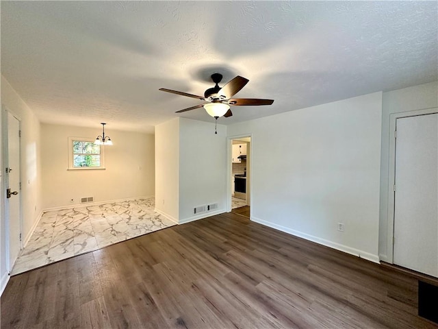 empty room with ceiling fan with notable chandelier and hardwood / wood-style flooring