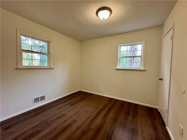 empty room with dark hardwood / wood-style flooring and a textured ceiling