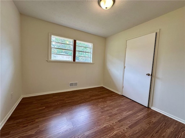 empty room featuring dark wood-type flooring and a textured ceiling