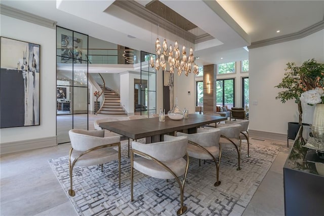 dining area with ornamental molding, a towering ceiling, a tray ceiling, and a notable chandelier