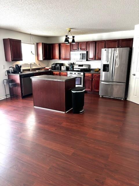 7178 Glaspie Way, Atlanta, GA 30349 - kitchen featuring appliances with stainless steel finishes, dark countertops, dark wood finished floors, dark brown cabinets, and a textured ceiling