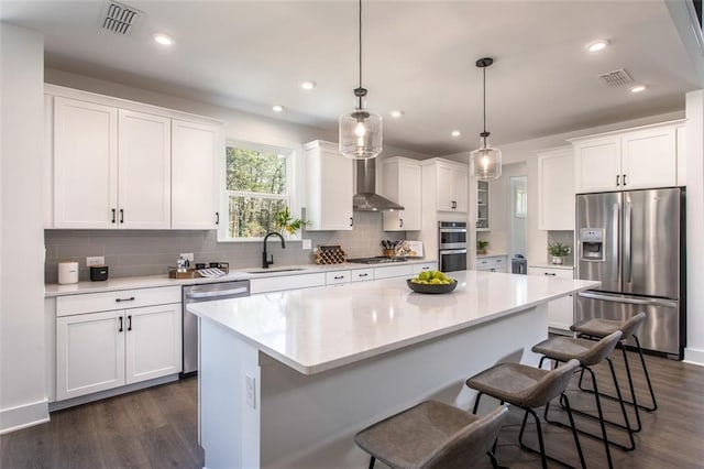 kitchen featuring white cabinets, a kitchen island, pendant lighting, and appliances with stainless steel finishes