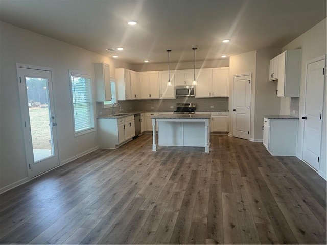 kitchen featuring stainless steel appliances, a center island, dark wood finished floors, and decorative backsplash