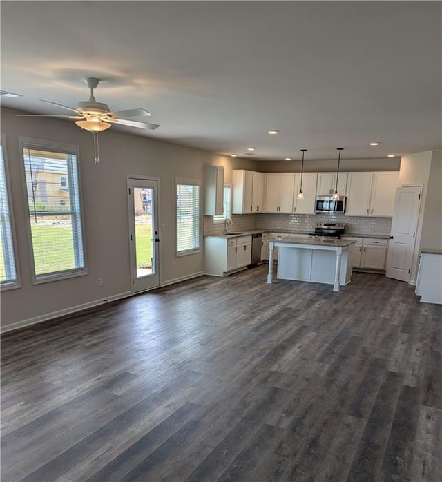 kitchen featuring appliances with stainless steel finishes, open floor plan, white cabinets, and tasteful backsplash