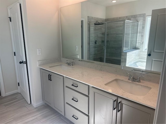 bathroom featuring a stall shower, a garden tub, a sink, and double vanity