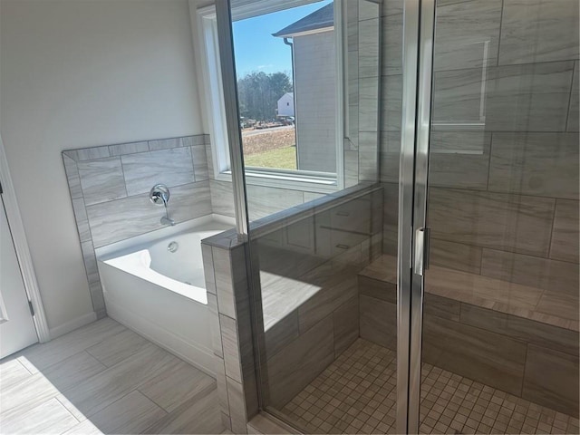 bathroom featuring a shower stall and a bath