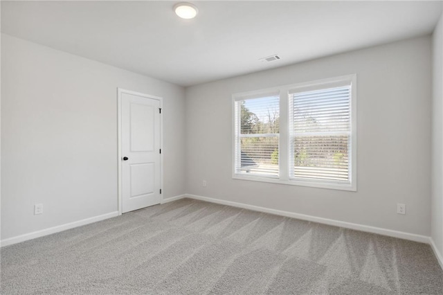 carpeted spare room featuring visible vents and baseboards