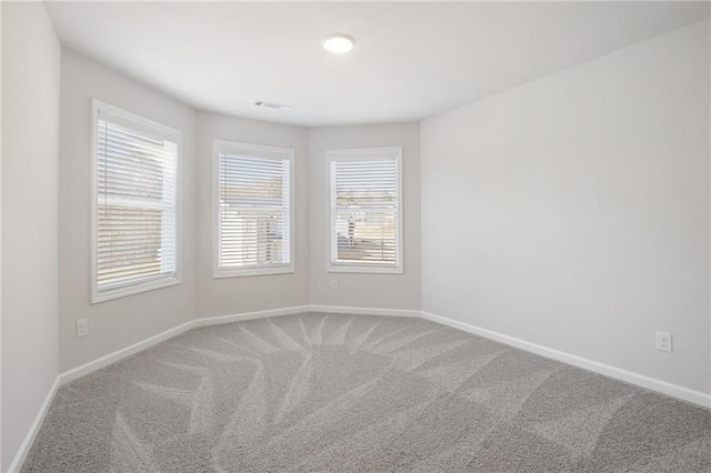 carpeted empty room featuring baseboards and visible vents