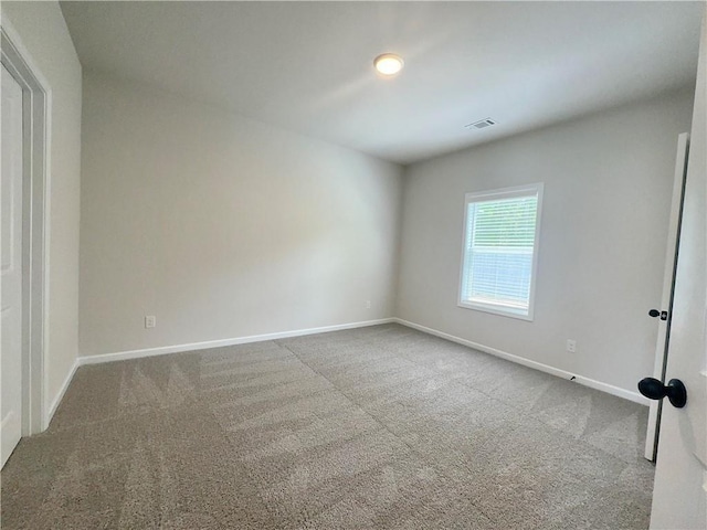 empty room featuring carpet floors, baseboards, and visible vents