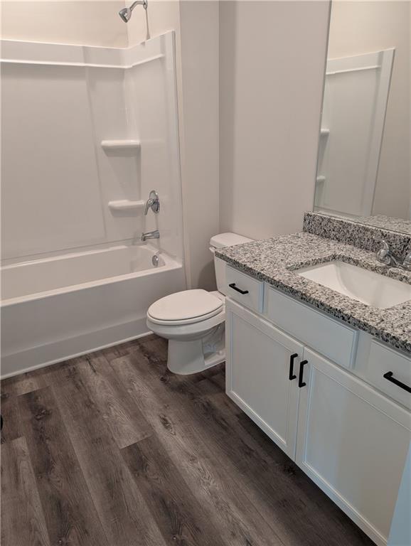 full bathroom with  shower combination, vanity, wood finished floors, and toilet