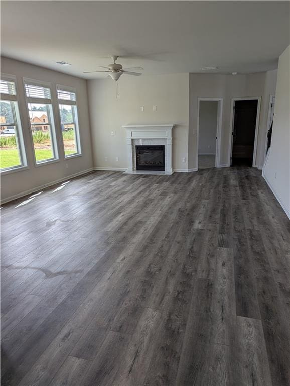 unfurnished living room featuring dark wood-style floors, a fireplace, baseboards, and ceiling fan