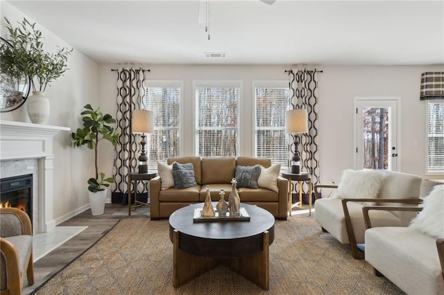 living area featuring wood finished floors, visible vents, baseboards, and a premium fireplace