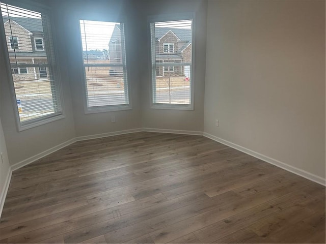 unfurnished room with dark wood-style floors and baseboards