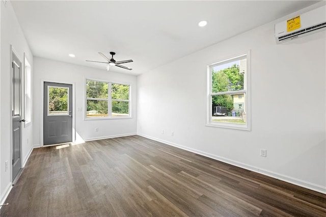 empty room with dark hardwood / wood-style floors, ceiling fan, and a wall unit AC