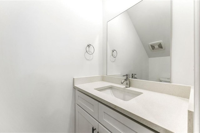 bathroom with vanity, toilet, and vaulted ceiling