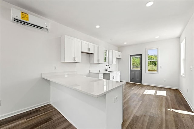 kitchen featuring sink, an AC wall unit, white cabinets, kitchen peninsula, and dark hardwood / wood-style flooring