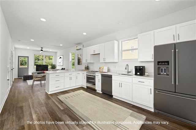 kitchen with dark wood-type flooring, sink, white cabinets, kitchen peninsula, and appliances with stainless steel finishes