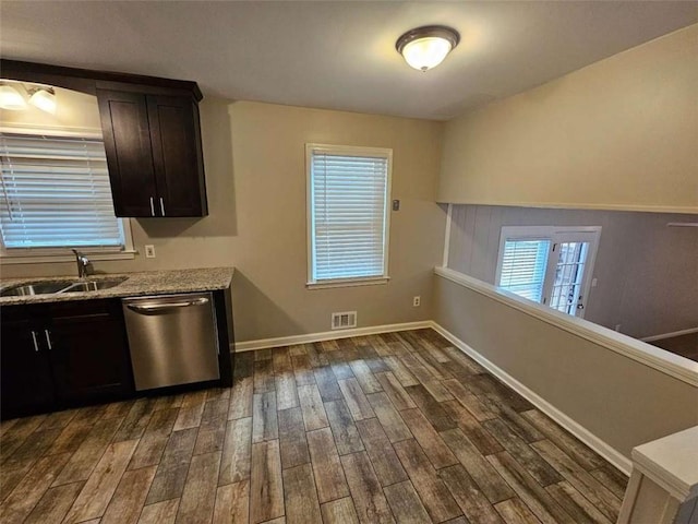 kitchen with dark wood-type flooring, sink, stainless steel dishwasher, light stone countertops, and dark brown cabinetry