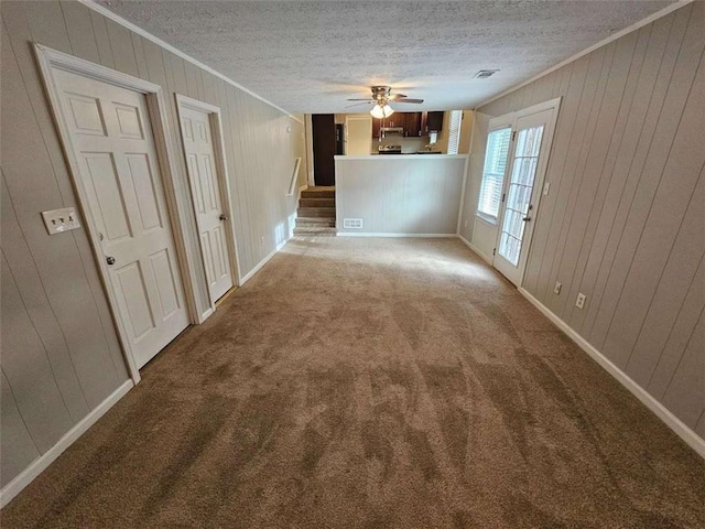 carpeted spare room featuring ceiling fan, a textured ceiling, and wooden walls