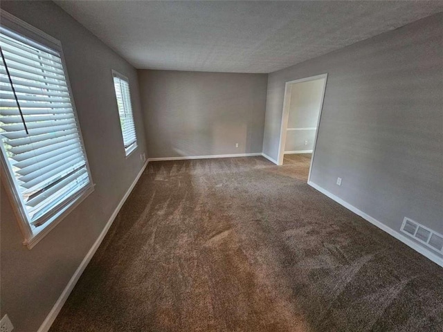 empty room with carpet and a textured ceiling