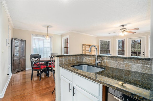 kitchen with sink, white cabinetry, dark stone countertops, pendant lighting, and hardwood / wood-style floors