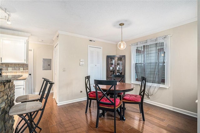 dining area featuring dark wood-type flooring, ornamental molding, electric panel, and a textured ceiling