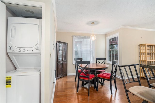 dining room featuring wood-type flooring, stacked washer / drying machine, a textured ceiling, and ornamental molding