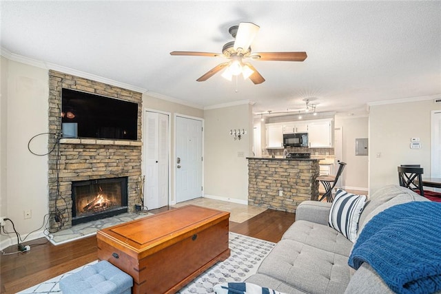 living room with dark hardwood / wood-style flooring, crown molding, a fireplace, and ceiling fan