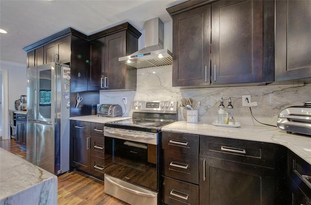 kitchen with appliances with stainless steel finishes, decorative backsplash, wall chimney exhaust hood, dark wood finished floors, and crown molding