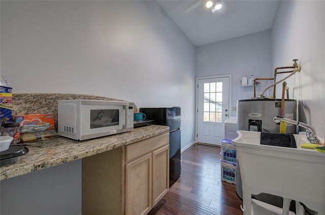 kitchen featuring dark wood-style flooring, water heater, light brown cabinetry, vaulted ceiling, and a sink