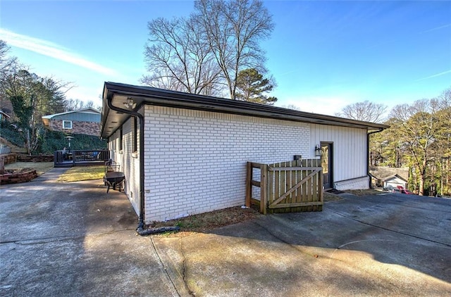 view of side of property with brick siding, fence, and a gate